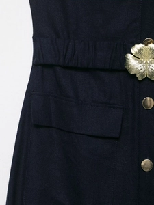 Close-up of linen midi dress featuring elastic waist and golden floral metal buckle detail