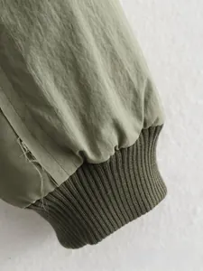 Gros plan sur le poignet d'une veste vert olive avec texture en tricot côtelé coupe-vent
