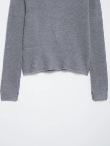 Close-up detail of ribbed cuffs and hem on a grey knitted crewneck sweater for women