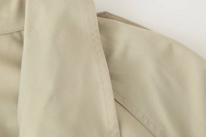 Macro shot of khaki double-breasted jacket showing twill fabric texture and fine stitching