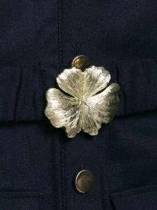 Close-up of golden flower buckle and round button on navy linen midi dress texture