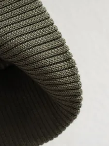 Gros plan détaillé des poignets côtelés sur un blouson aviateur zippé vert olive
