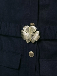 Detail eines marineblauen Leinen-Midikleids mit goldener Blumenschnalle und Knopf