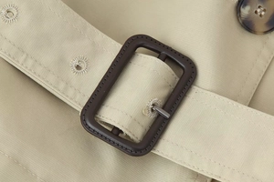 Macro detail of khaki twill trench coat belt with a dark brown rectangular buckle