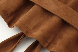 Close-up of the fine stitching and soft suede texture on a dark brown lapel jacket