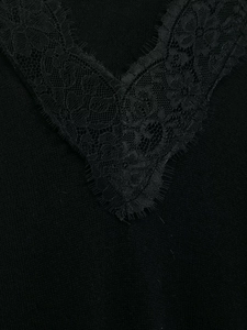 Détail du col en V avec dentelle florale délicate sur un pull en maille noir en laine mélangée