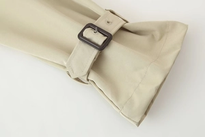 Detailed macro view of khaki trench coat sleeve featuring twill fabric and adjustable buckle