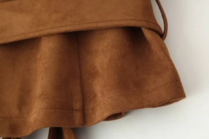Detail of brown faux suede fabric showing ruffled hem and precise stitching craftsmanship