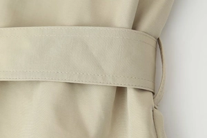 Detailed macro view of khaki twill fabric texture and belt buckle on short trench coat
