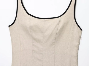 Close-up of contrast piping on beige linen dress with princess seams and side zipper