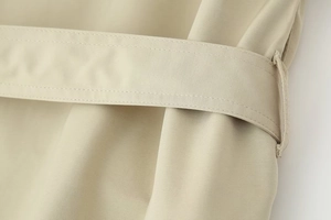 Detail view of double-stitched seams and twill texture on light khaki trench coat belt