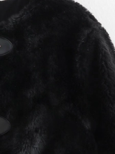 Detail of black faux fur jacket texture featuring high-density plush and leather buckle base