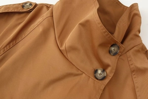 Detail of high funnel neck with tortoise shell buttons on tan twill cotton trench coat