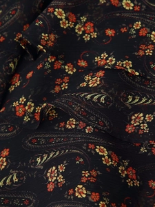 Close-up of black floral chiffon fabric with paisley patterns and pleated texture