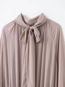 Detalle de blusa satinada malva con cuello de lazada y elegantes pliegues en el cuello alto