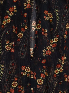 Detail shot of black chiffon fabric with orange floral paisley pattern and pleated texture