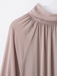Detalle de blusa de gasa rosa palo con cuello alto y pliegues delicados de textura