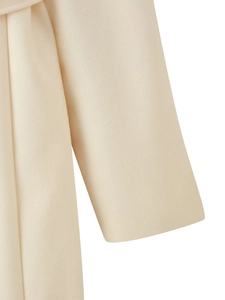 Detail shot of cream wool coat sleeve and waist belt with premium soft texture