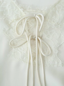Détails de dentelle délicate et de rubans en satin sur une robe blanche élégante