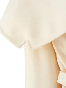 Close-up of cream wool coat detailing geometric zigzag edges and soft textured fabric