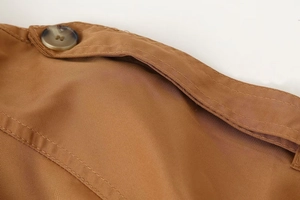 Detail of shoulder epaulette on khaki twill trench coat with marble pattern button