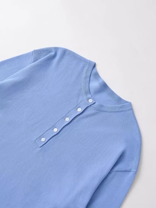 Close-up of light blue knit sweater with round neck and five small white buttons