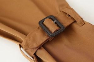 Detailed view of the brown twill trench coat cuff featuring a dark buckle and fine stitching