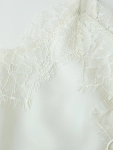 Vue macro de dentelle de cils blanche et de maille géométrique sur une robe nuisette