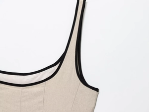 Close-up of contrast black piping on beige linen midi dress square neckline and strap