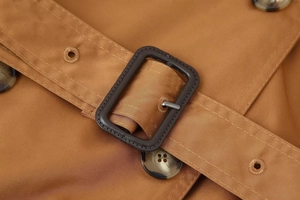 Detailed macro shot of camel twill coat belt with rectangular buckle and tortoise buttons