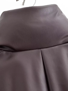 Macro view of dark brown faux leather fabric texture with elegant pleats and waist details