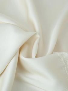 Gros plan d'un tissu en satin crème avec bordure délicate en dentelle de cils blanche