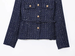 Close-up of navy tweed fabric with shimmering sequins and embossed gold buttons