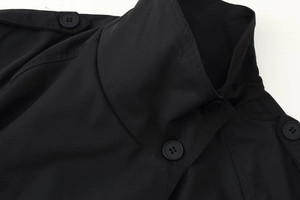 Close-up of double-breasted trench coat featuring epaulettes and matte black buttons