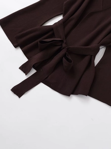 Dettaglio ravvicinato di un cardigan in maglia marrone cioccolato con cintura in vita
