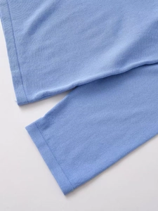 Macro detail of soft light blue knit texture and tight jersey stitch pattern on sleeve cuff