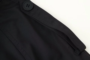 Macro detail of twill fabric texture and shoulder button on black double-breasted trench coat