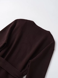 Dettaglio macro del cardigan in maglia marrone scuro con cuciture su scollo e spalla posteriore