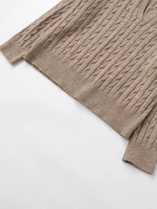 Detail of cable knit pattern and ribbed cuff on a light brown V-neck autumn sweater