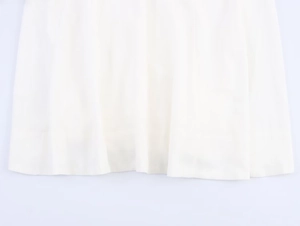Detail of white linen midi dress hemline showing soft fabric texture and natural drape