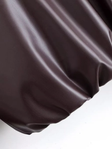 Detailed macro view of dark brown faux leather texture with soft matte finish folds
