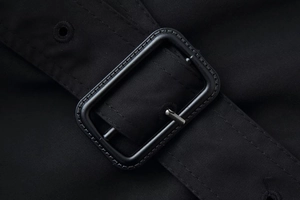 Close-up of black twill fabric and matte rectangular buckle with engraved texture details