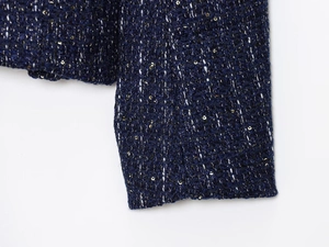 Close-up of luxury dark blue tweed jacket with golden sequins and textured weave details