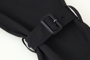 Detailed close-up of the black twill trench coat cuff with a buckle and metal eyelets