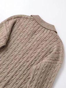 Detail of brown cable-knit texture and back collar on a thick wool polo sweater