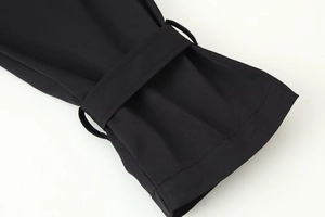 Detail of double-breasted trench coat cuff with black woven fabric and decorative strap