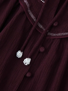 Detail of burgundy shirt featuring zig-zag embroidery and beaded drawstring neck ties