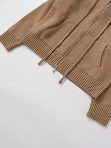 Detailed macro view of the knitted texture and silver metal zipper on this brown cardigan
