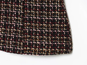 Macro shot of colorful bouclé tweed fabric with metallic gold thread and fringe detail