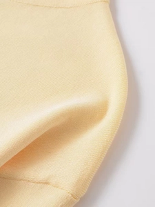 Detailed close-up of light yellow knit sweater fabric with ribbed cuff textures